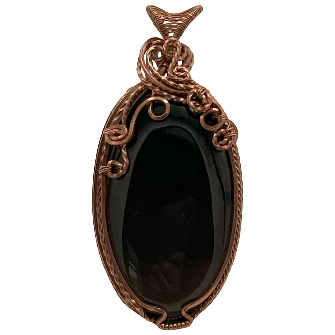 Decorative pendant with a black stone and intricate copper design on a white background